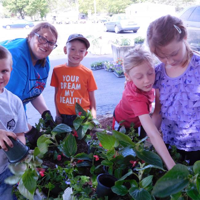 Adult and youth gathered around plants