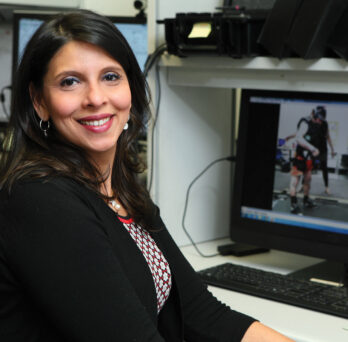 Tanvi Bhatt sitting in front of a desktop computer.
                  