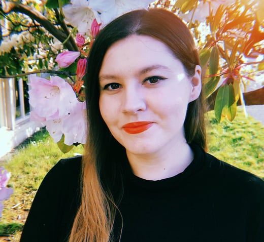 Jenna James, a woman with long brown hair wearing a black sweater and red lipstick.