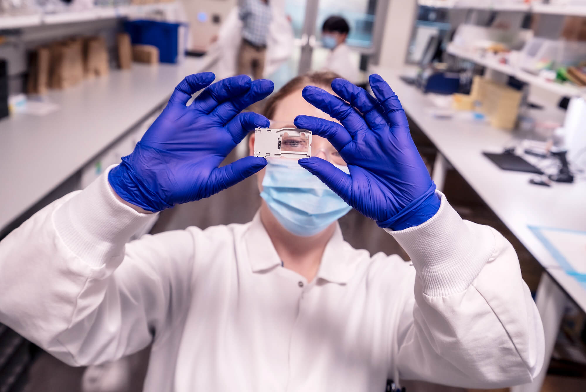 Female researcher holding up a small transparent sample in a glass container up to the light