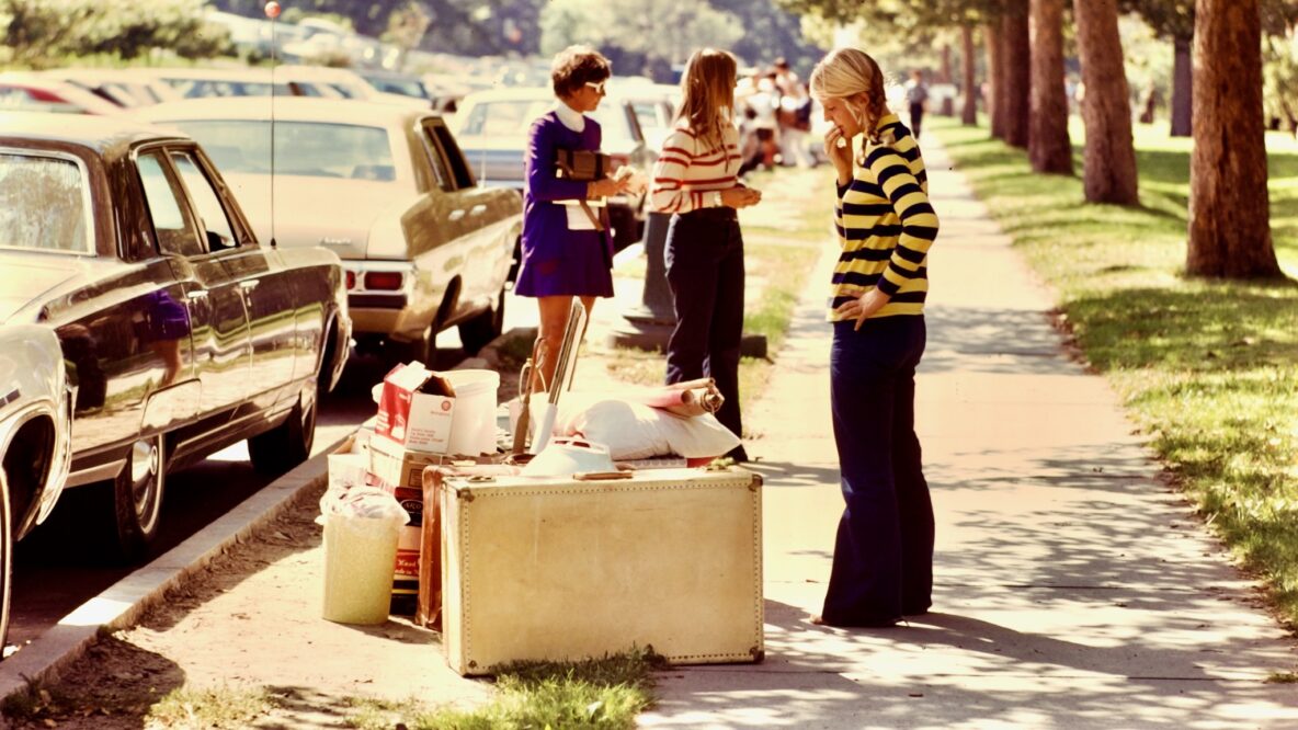 a student takes a quiet moment to contemplate unloaded belongings before moving them into a campus residence, 1970