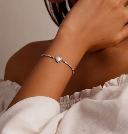 A model wearing a sterling silver bracelet with a opal heart.