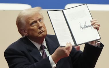 President Donald Trump holds up an executive order after signing it at an indoor Presidential Inauguration parade event in Washington, Monday, Jan. 20, 2025. (AP Photo/Matt Rourke)