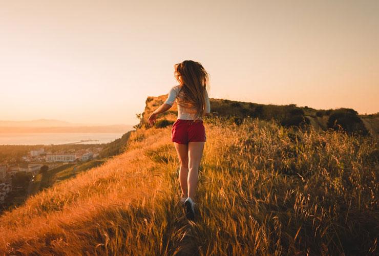 The Power of Nature to Heal Your Body and Mind by Sofia Alves. Photograph of a woman running through grass by Joao Ferreira