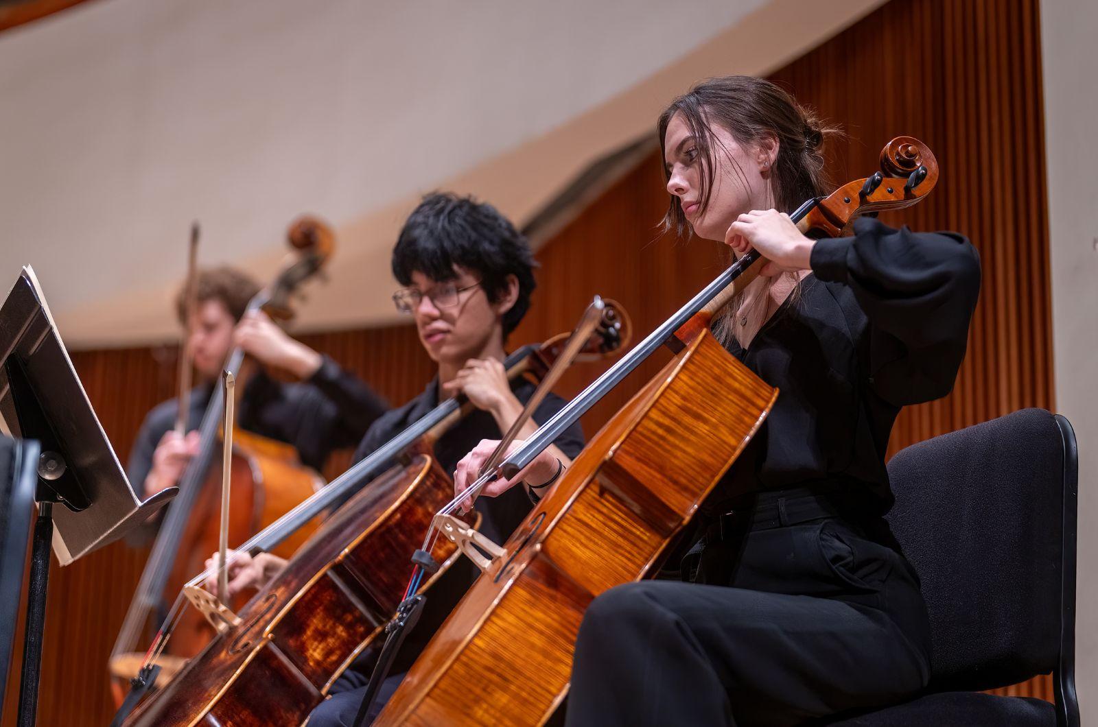 Members of the UMD Symphony Orchestra play cellos during a concert.