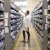 Pharmacist stocking shelves in drug store aisle