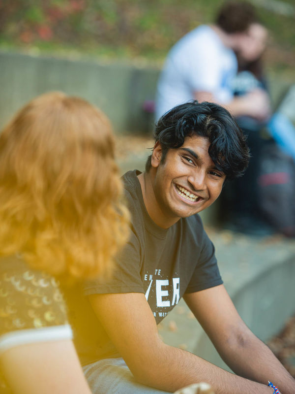 A male and female student sit on steps and talk