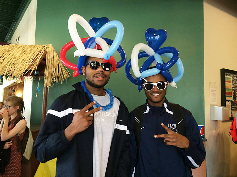 Two male students wear balloon animal hats