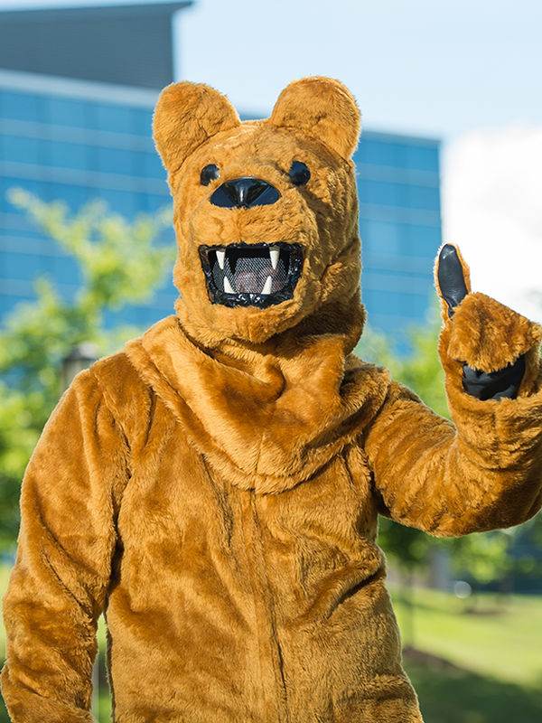 Behrend Lion with paw raised in #1 gesture in front of academic building.