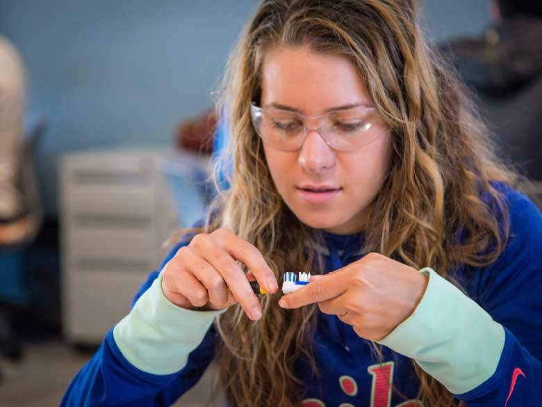 A student looks at toothbrushes in a classroom.