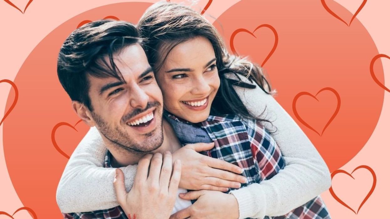 young couple hugging and smiling against a pink heart background