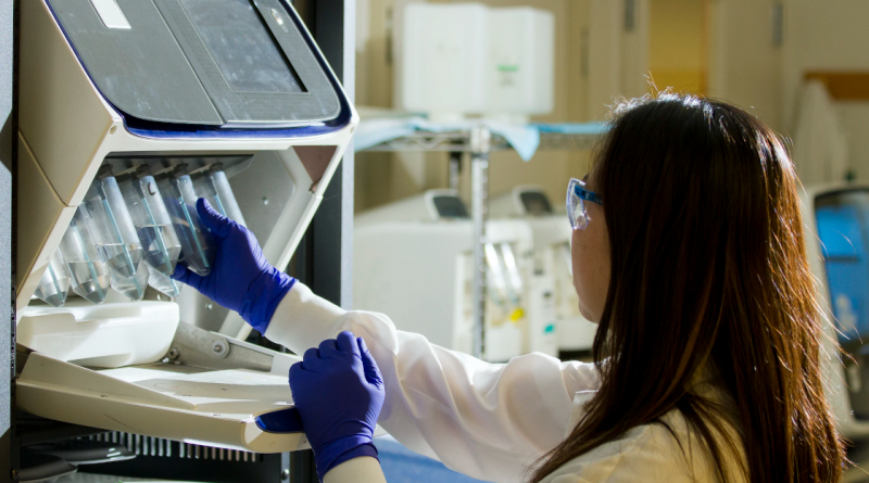 A researcher placing specimens into a machine.