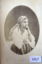 a young woman leans against a striped textile, resting her chin against her hand