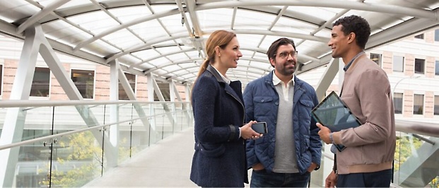 Three people standing on foot over bridge.