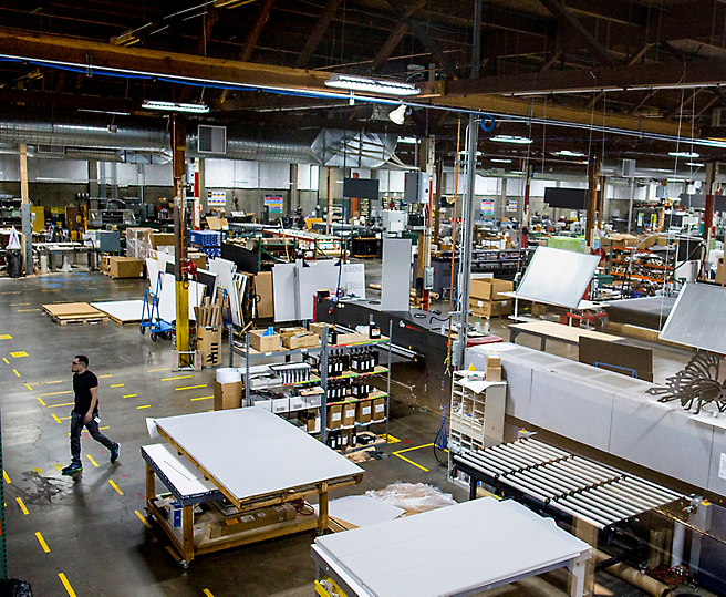 A person walking through a busy manufacturing workshop with various stations and materials.