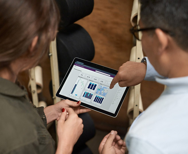 Two individuals reviewing data on a tablet.