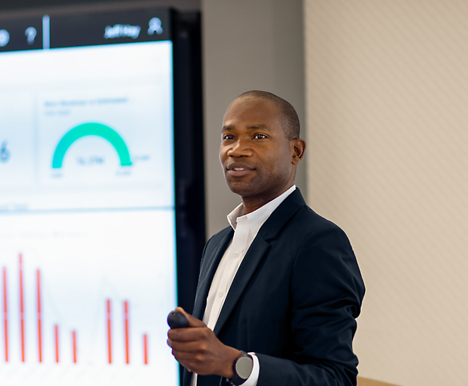 A man in a suit standing in front of a screen.