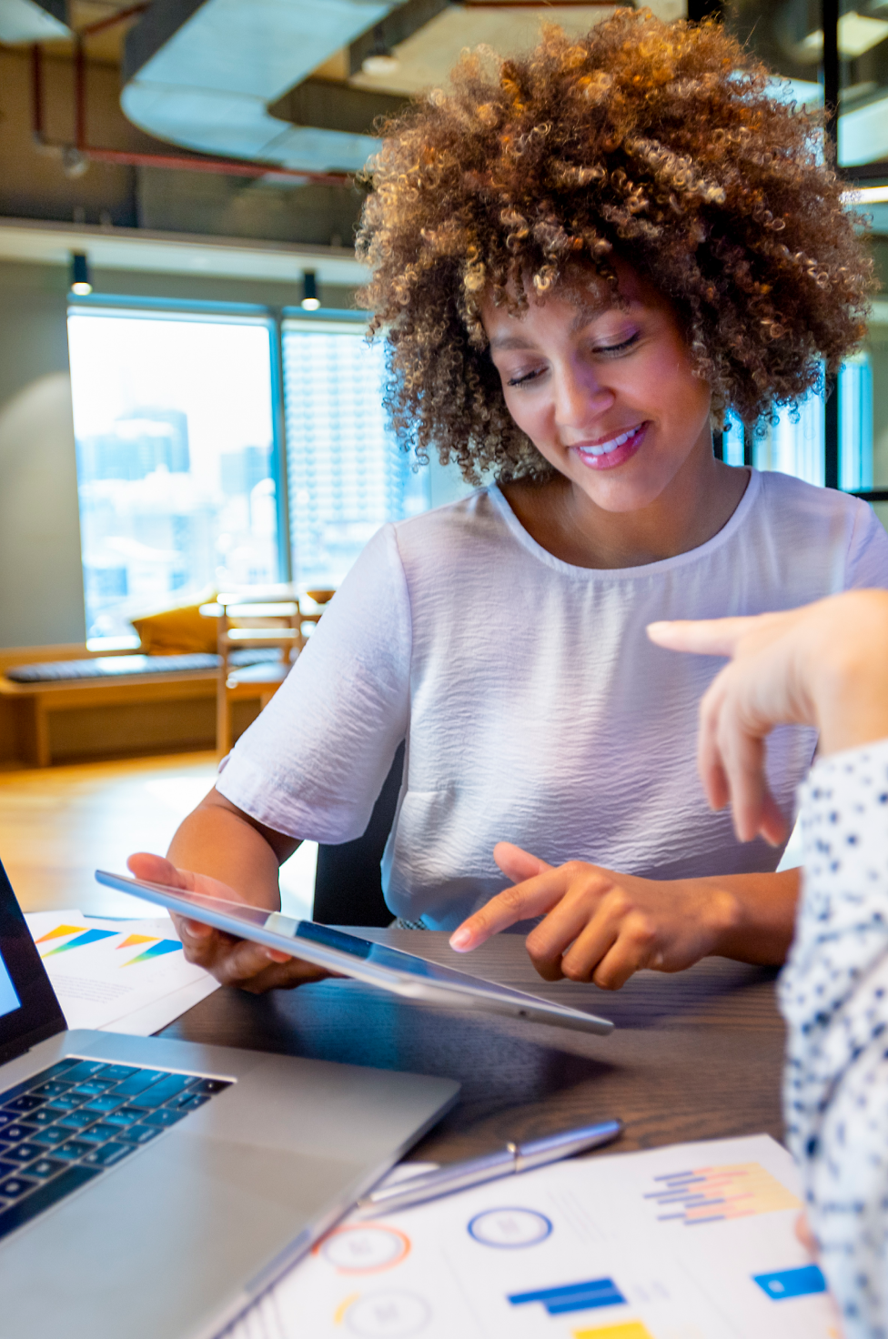 A woman in office working on her tablet and talking