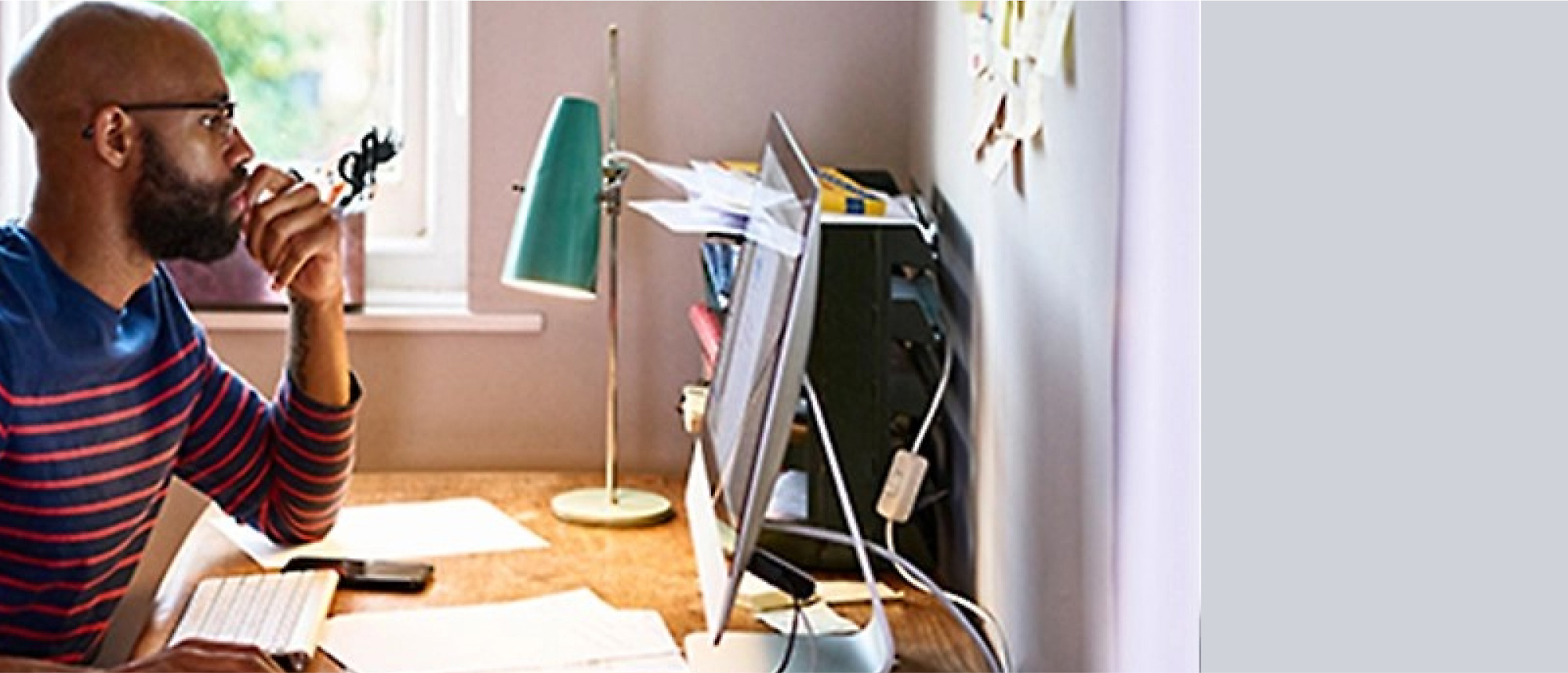 A man sitting at a desk looking at a computer screen.