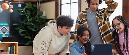 A group of students looking at a laptop in a classroom.