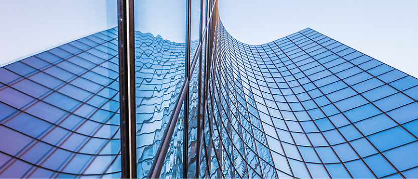 Modern glass skyscraper with a curved facade reflecting the sky and surrounding buildings.