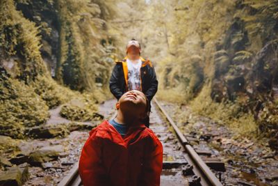 Son with father standing on railroad track in forest