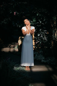 Portrait of young woman standing against plants