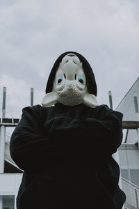 Man wearing mask while standing against sky