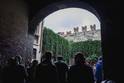 Rear view of people standing below archway