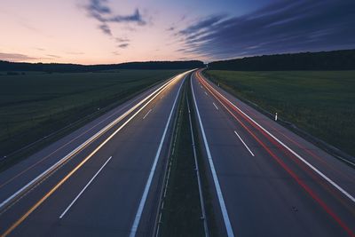 Light trails on highway against sky