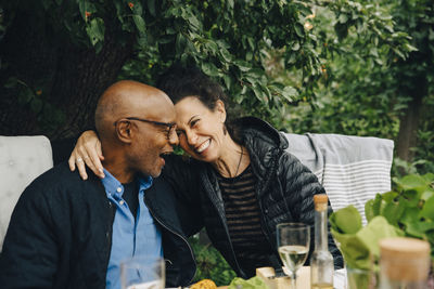 Cheerful senior man and woman enjoying while sitting at dinning table during garden party