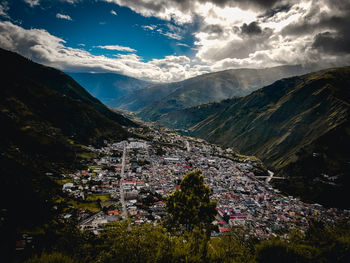 Aerial view of townscape by mountains against sky