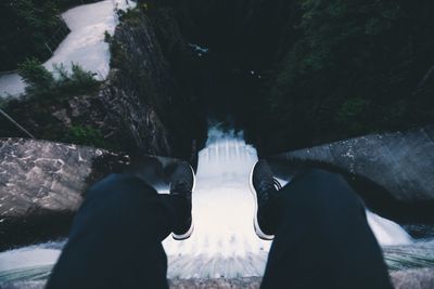 Low section of man sitting on top of dam