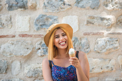 Portrait of a beautiful young woman drinking against wall