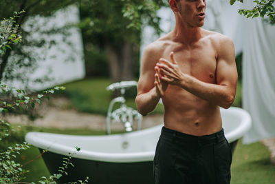 Midsection of shirtless man standing against blurred background