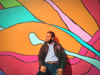 Man against colorful graffiti wall on sunny day