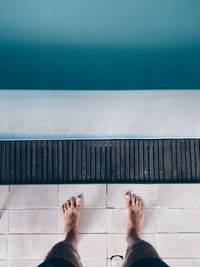 Low section of man standing by swimming pool