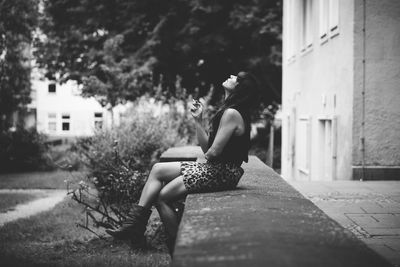 Full length of woman sitting on retaining wall