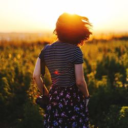 Woman standing on field at sunset