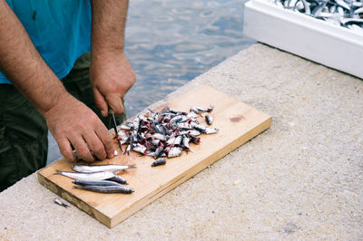 Midsection of man cutting fish on board