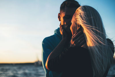 Close-up of couple embracing against blue sky