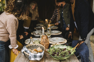 Male and female friends arranging food plates on dining table during social gathering