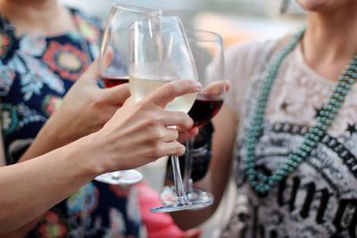 Midsection of women toasting wineglasses