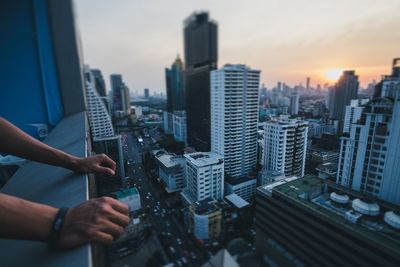 Cropped hands of person by window sill in city