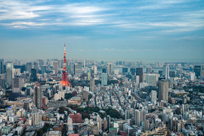 Aerial view of buildings in city against cloudy sky