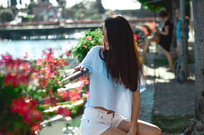 Rear view of woman standing by flowering plants