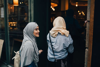 Rear view of young women entering doorway