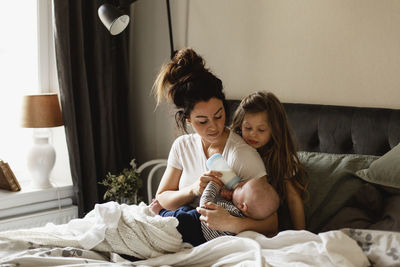 Mother feeding baby on bed