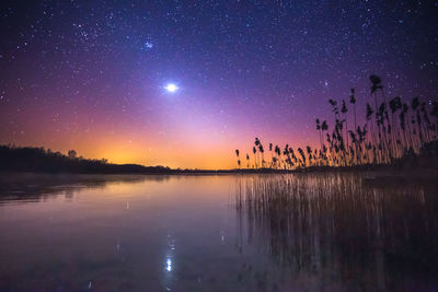 Scenic view of lake against sky at night