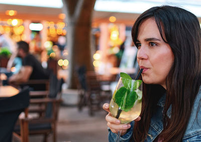 Woman drinking cocktail on a night out in town. bar, lifestyle, summer.